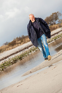 精力充沛的人摄影照片_跑沿海滩的年长精力充沛的人