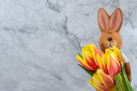 与黄色红色郁金香花的瓷复活节兔子