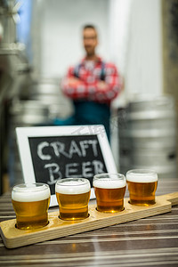 工厂标语牌摄影照片_啤酒取样器托盘上的四杯精酿啤酒