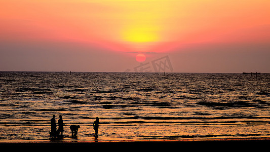 夕阳的天空摄影照片_现出轮廓的人走在海上与夕阳的天空