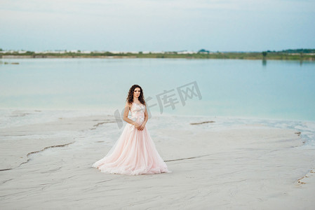 穿着粉红色连衣裙的女孩正沿着白色沙滩行走