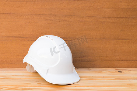 白色安全头盔塑料工程施工在木地板桌背景上带复制空间添加文本