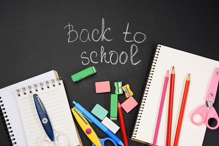 学校用品：多彩多姿的木铅笔、笔记本、卷笔刀和回到学校的白色粉笔题词