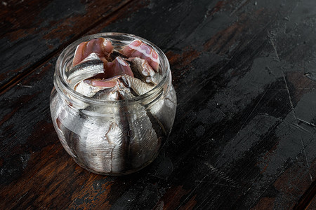 盐渍凤尾鱼片，在玻璃罐中，在旧的深色木桌背景上 ，有复制空间和文本空间