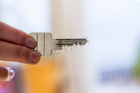 居住空间摄影照片_搬进新家：拿着钥匙的手的特写。