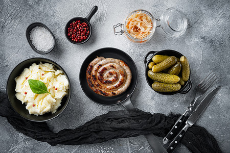 炸巴伐利亚德国 Nurnberger 香肠配酸菜，铸铁煎锅中的土豆泥，灰色背景，俯视平躺