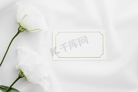 婚礼请柬或礼品卡和丝绸织物上的白玫瑰花作为新娘平面背景、空白纸和假日品牌、平面布局设计