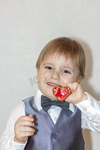 一个小男孩拿着一颗红心，这是情人节主题的概念。