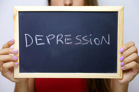 身份不明的年轻女子拿着黑板上写的抑郁症。