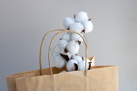 灰色背景上带棉花花的有机环保纸袋。