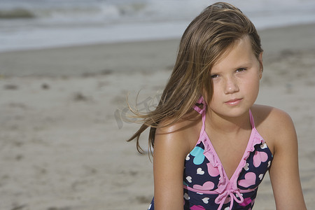 头部摄影照片_坐在沙滩上的小女孩