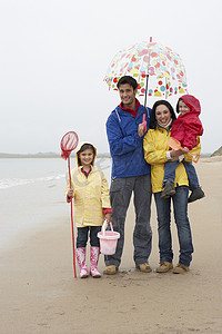 沙滩上带伞的幸福家庭