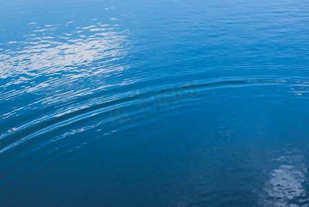 平静的水面上泛起小涟漪，反射出深蓝色的光。