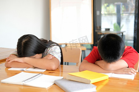 疲惫不堪的女男孩学生在图书馆学习艰苦考试后睡觉