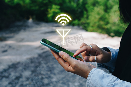 智能网摄影照片_人们使用智能手机在离网无电源空间区域或树林中寻找信号 wifi。