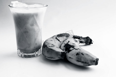 生有机新鲜香蕉及其冰沙或奶昔或香蕉牛奶，放在玻璃杯中，用白色隔开。