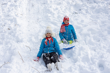 两个女孩从山上滚下来，坐在雪地里，高兴地看着画面
