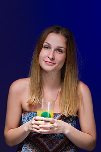 喝饮料的女孩摄影照片_蓝色背景下喝鸡尾酒的女孩