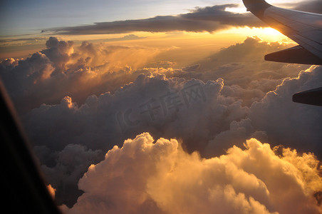 飞机上的金色光云，从飞机上看，在金色的夕阳照亮空气中，雄伟的云彩飞翔