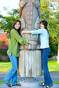 两个年轻的混血少女在公园里拥抱苏的图腾柱