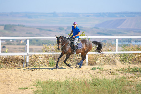 克里斯丁摄影照片_骑马的女孩在畜栏里骑马