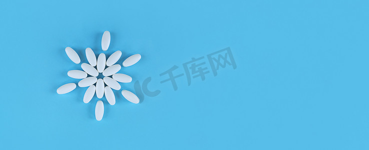由白色片剂在蓝色背景上制成的花形，带有复制空间。