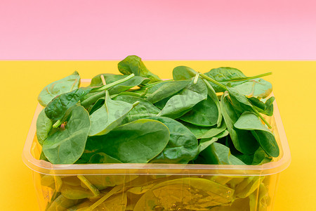 黄色背景透明塑料包装中的新鲜菠菜叶