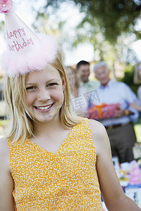 人物大头摄影照片_戴着生日帽的女孩站在聚会外