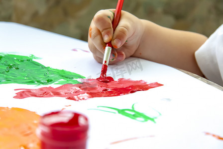 一个孩子的手拿着画笔，用大笔画画纸。