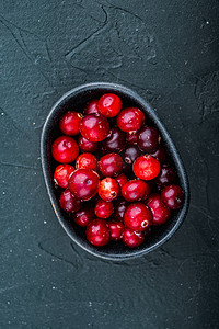 中野三玖鼠标摄影照片_黑色碗中的成熟蔓越莓，顶视图，黑色背景