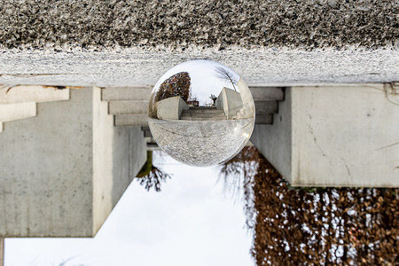 水晶城市摄影照片_城市街道上的小混凝土楼梯，周围的灌木丛反映在水晶玻璃透镜球中