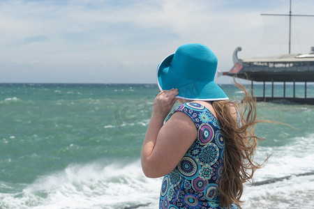 海景模糊背景上戴蓝色帽子的女孩。
