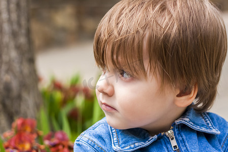 小孩眼睛摄影照片_一个小孩在绿色背景下在户外微笑的特写肖像。