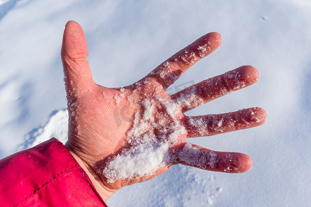 雪摄影照片_一个男人在冬天寒冷的手掌中握着一把新鲜的雪