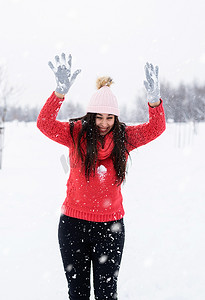 穿着红色毛衣的黑发年轻女子在公园里玩雪