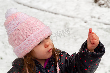 一个戴着粉色帽子的女孩在雪地里玩耍
