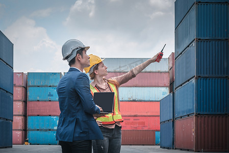 进出口运输行业的集装箱航运物流工程、运输工程师团队合作在港口装船码头控制管理集装箱。