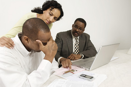 一位非洲裔美国妇女安慰男人，财务顾问指着办公桌上的信用卡