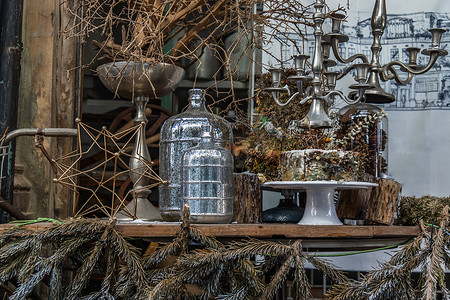 古色古香的烛台和干植物、干花、带玻璃瓶的松果装饰在咖啡馆的木桌上。