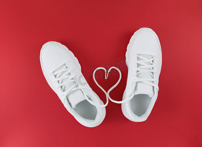 白色运动鞋和红色背景上鞋带的心形。