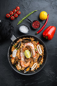 海鲜饭传统西班牙菜在煎锅中供应，黑色纹理表面，顶视图