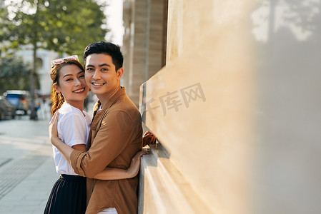 一对年轻夫妇在目的地城市拥抱的后视图，同时站在户外一家高档鞋店附近的购物区