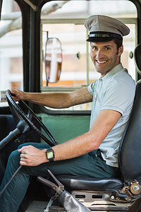 半幅方向盘摄影照片_驾驶公共汽车的微笑的公共汽车司机