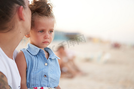 小女孩的哭泣摄影照片_哭泣的小女孩母亲女儿夏天海滩。