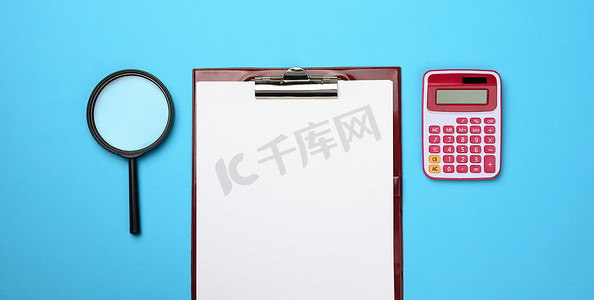 粉红色计算器、带空白白纸的文件夹和蓝色背景上的黑色放大镜。