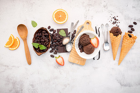 在白色石头背景上设置黑巧克力和可可粒的碗中的巧克力冰淇淋口味。