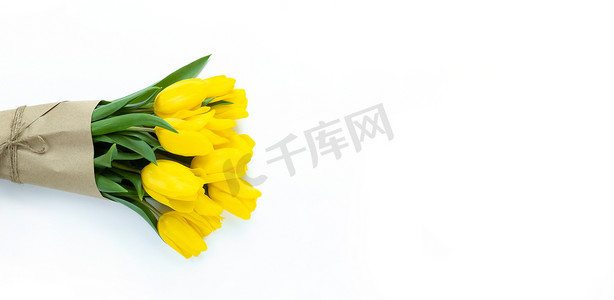 黄色郁金香花束包裹在白色背景的工艺纸中，带有复制空间。