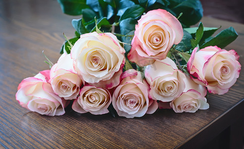玫瑰桌花摄影照片_桌面上的玫瑰花束。