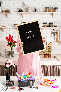穿着粉色裙子的女人拿着黑色信板，上面写着复活节快乐