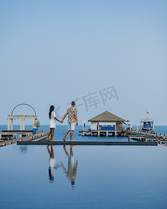 春堤摄影照片_泰国芭堤雅 Bangsaray 海滩的木码头，一对夫妇在泰国度假期间在木码头上散步